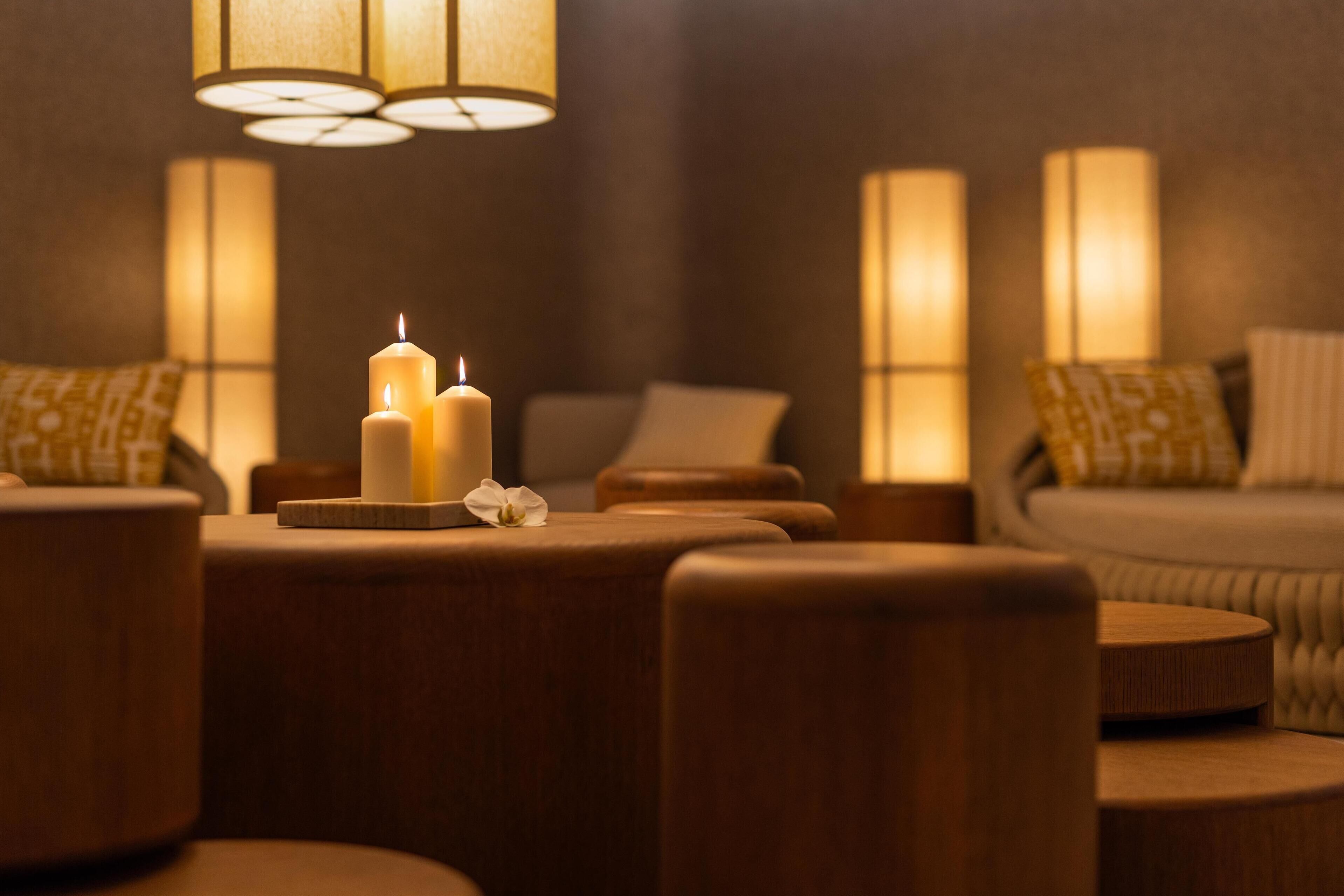 A cozy room with a sofa, a round table with candles, and ambient lighting.