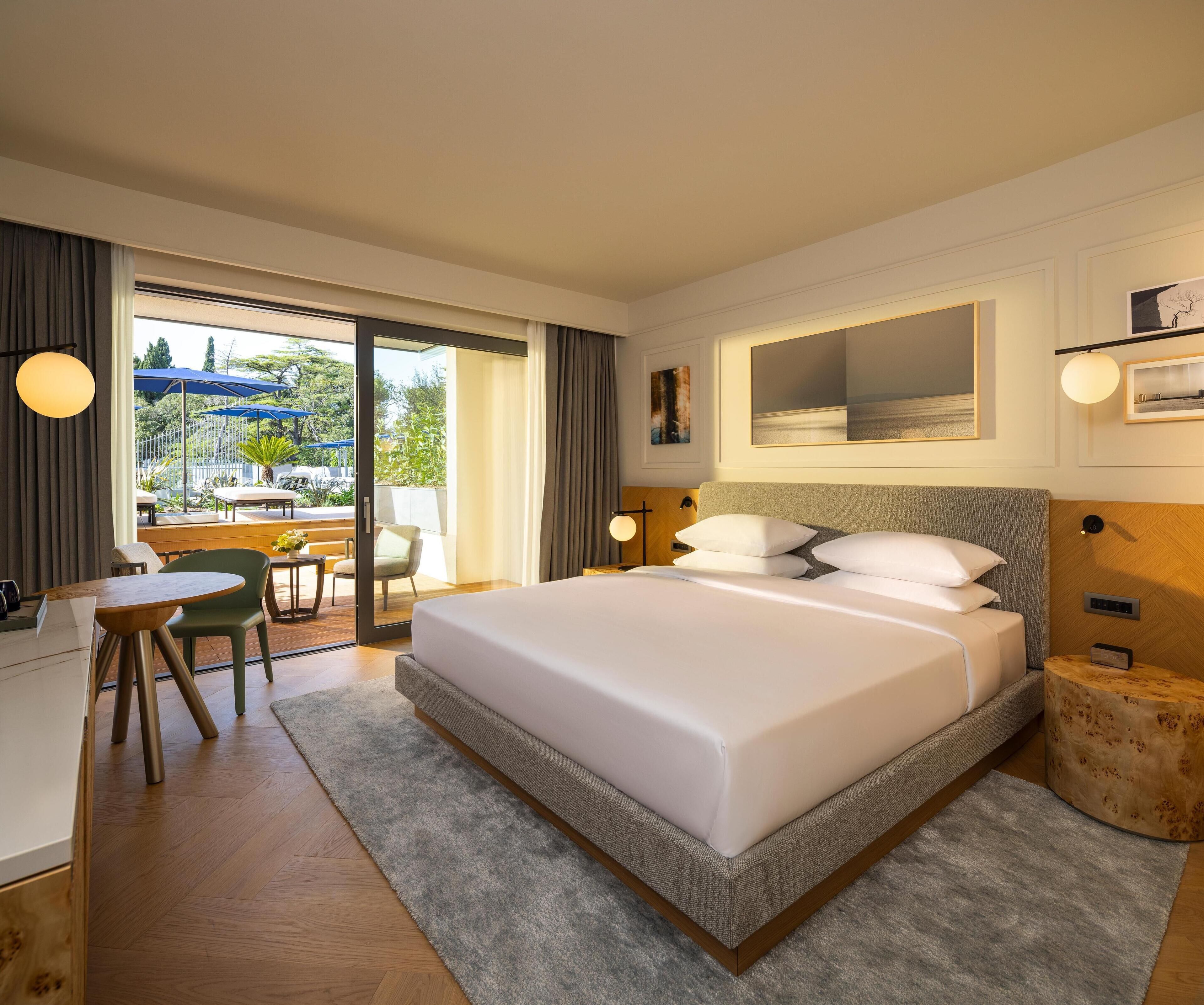 Camera d'albergo moderna con un letto grande, una scrivania e vista sullo spazio esterno.