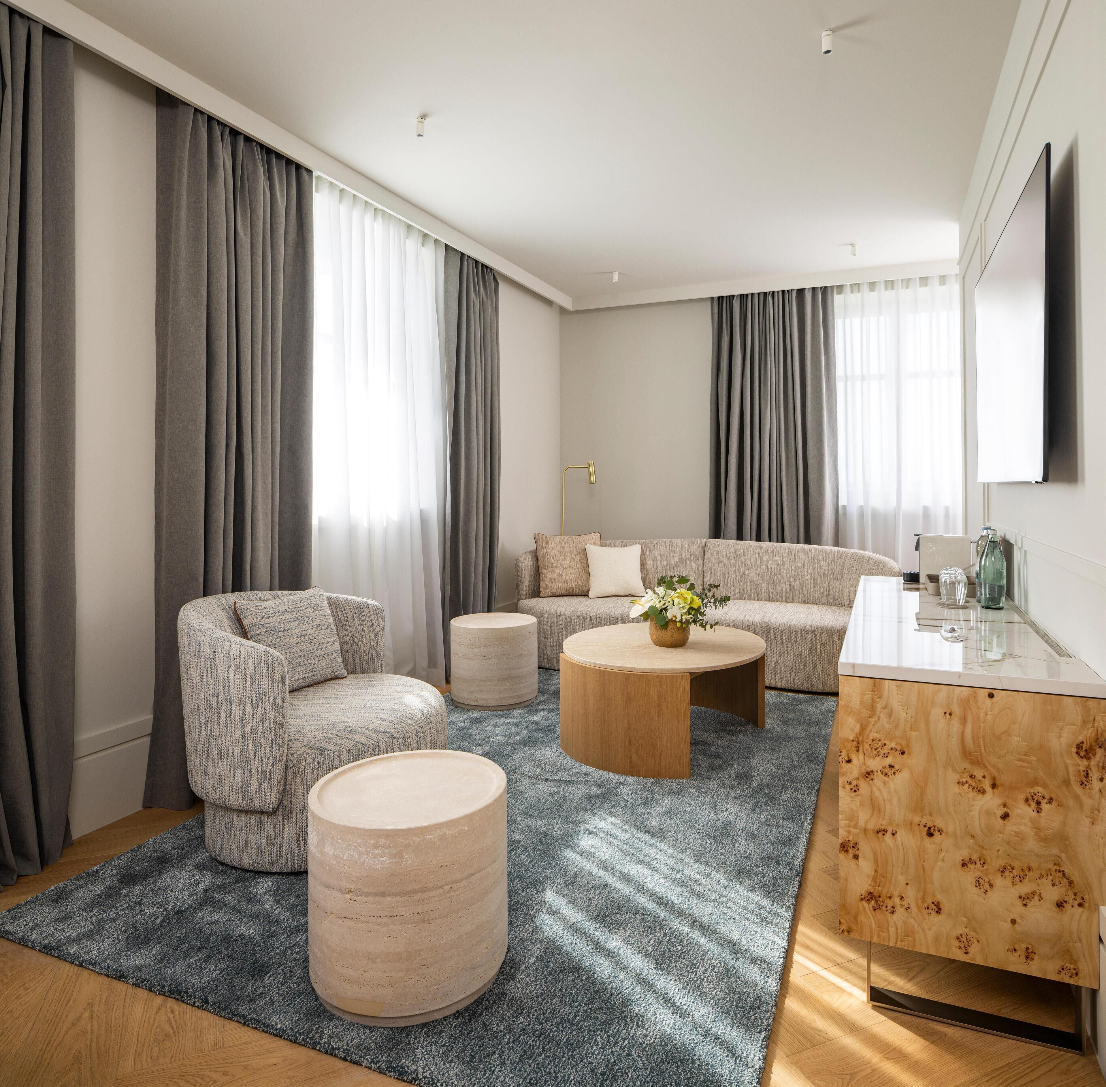 A modern living room with a sofa, armchair, round coffee table, and a wooden side table.