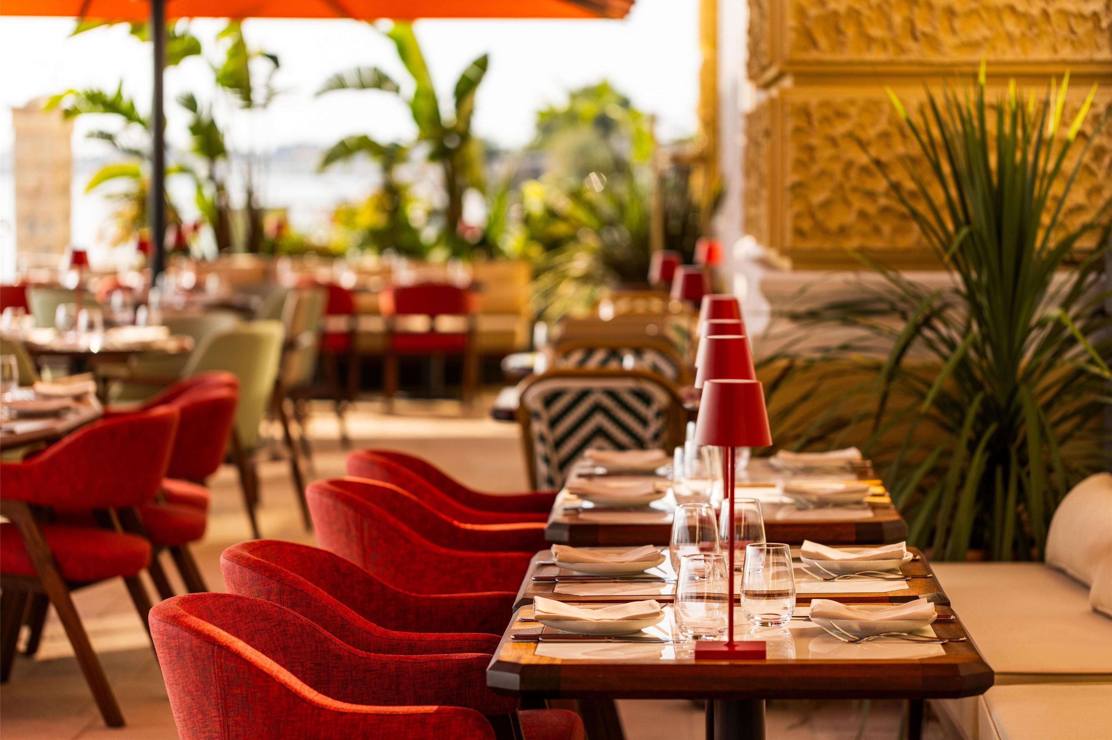 Un restaurante con sillas rojas, mesas de madera y un paraguas rojo.