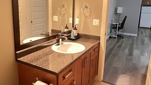 Une salle de bain équipée d’un lavabo, d’un miroir, d’un rouleau de papier toilette et d’un porte-serviettes.
