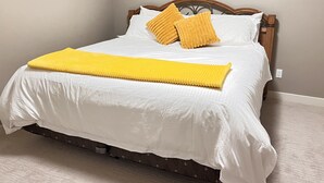 Un lit bien fait, avec du linge de lit blanc et un plaid jaune.