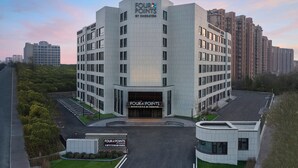 Een modern meerlaags hotel genaamd 'Four Points by Sheraton' met een opvallende ingang en een parkeerplaats.