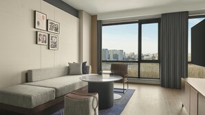 Ein modernes Wohnzimmer mit einer Couch, einem runden Couchtisch und Blick auf eine Stadtkulisse durch große Fenster.