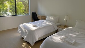 Habitación de hotel con dos camas, un escritorio, una silla y una ventana con vistas a zonas verdes.