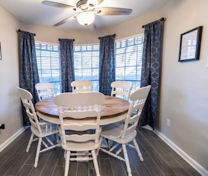 A dining area with a round wooden table, white chairs, and a ceiling fan. - 6S Hideout Houston (Houston)