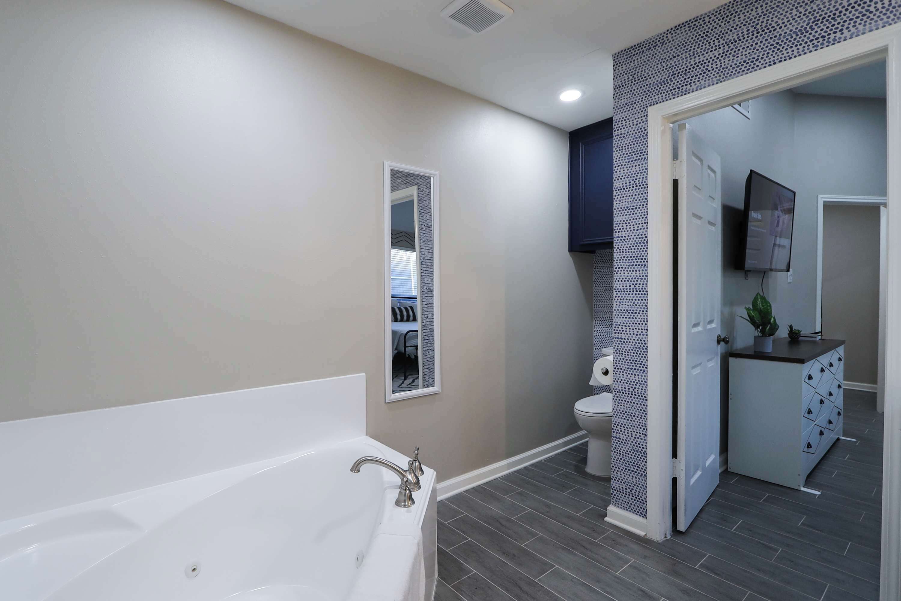 A modern bathroom with a bathtub, toilet, and a walk-in shower.
