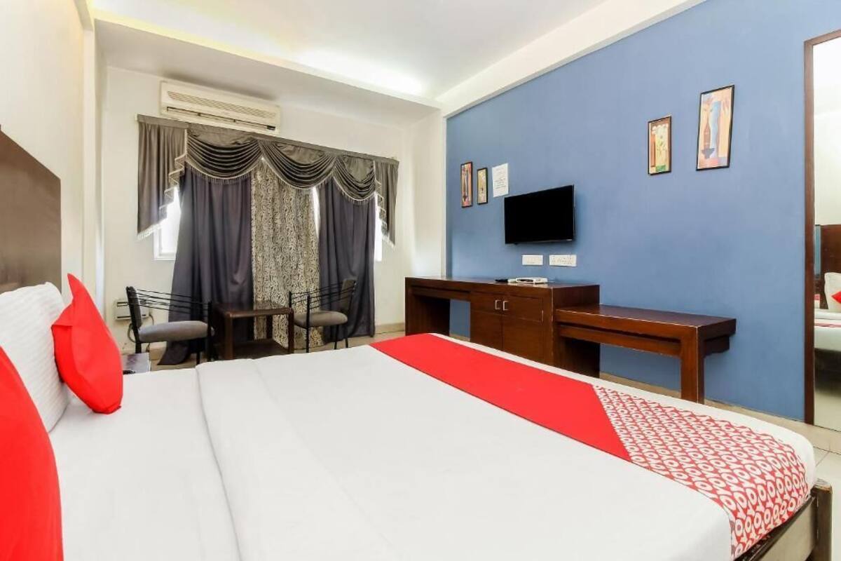 Een hotelkamer met een groot bed, een bureau, een stoel, een televisie en een raam met gordijnen.