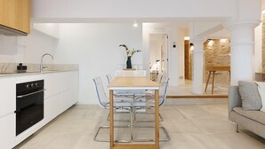 Una cocina moderna con armarios blancos, una mesa de comedor de madera y sillas transparentes.