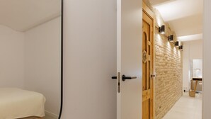 Un dormitorio con cama, una puerta de madera y pared de ladrillo.