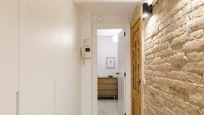 Un pasillo con una puerta blanca que da a una habitación con pared de ladrillo.