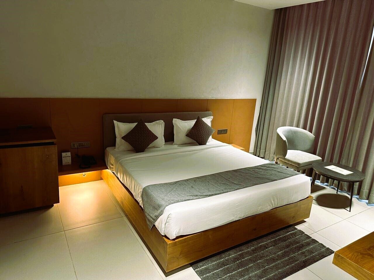 Una habitación de hotel con una cama grande, un cabecero de madera, un escritorio, una silla y una mesita.