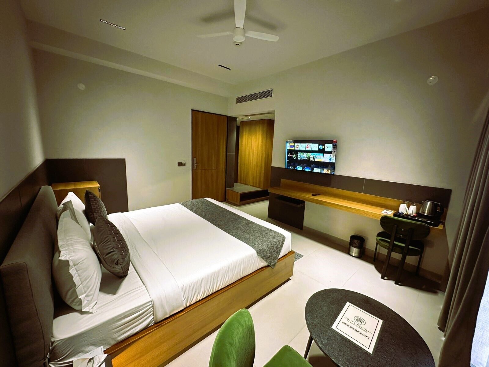 A modern hotel room with a bed, a desk, a television, and a small table.