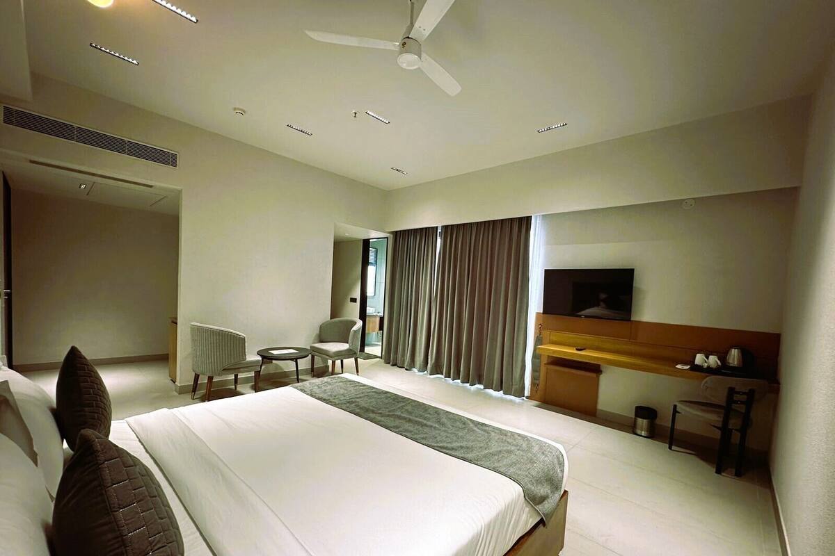 Een hotelkamer met een groot bed, een bureau met een televisie, een stoel en een klein tafeltje.
