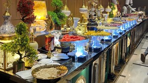 Un lungo tavolo del buffet con diversi cibi e elementi decorativi in una stanza ben illuminata con pannelli in legno.
