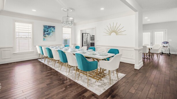 A spacious dining area with a long table, blue and white chairs, and a chandelier. - 6,500 Sq Ft Masterclass Style Meets Elegance (Arlington)