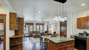A spacious kitchen with wooden cabinets, a granite countertop, and a dishwasher. - Main Street Station Suite - Ski-In, Ski-Out, Pool, Hot Tub (Breckenridge)