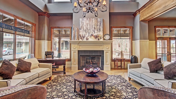 A spacious lobby with a fireplace, a chandelier, and a view of the street. - Main Street Station Suite - Ski-In, Ski-Out, Pool, Hot Tub (Breckenridge)