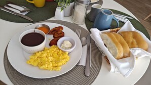A breakfast plate with scrambled eggs, black bean dip, plantains, and toast.