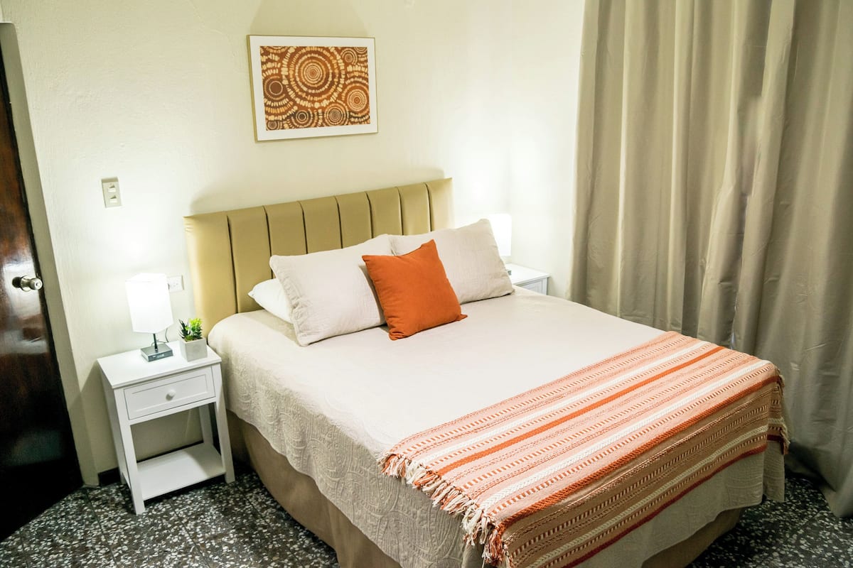 Une chambre d’hôtel avec un lit, une table de chevet, une lampe et une œuvre d’art murale.