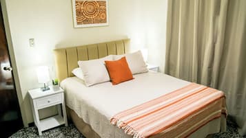 A hotel room with a bed, a nightstand, a lamp, and a wall art piece.