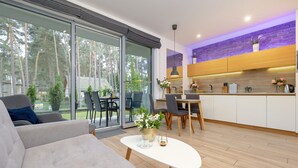 A modern living room with a sofa, a dining table, and a kitchen area with cabinets and a countertop. - Holiday Apartment Close to a Sandy Beach (Rewal)