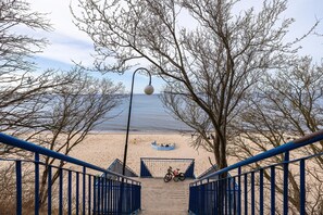 A beach view with a staircase leading to a sandy area, a bicycle, and a boat. - Holiday Apartment Close to a Sandy Beach (Rewal)
