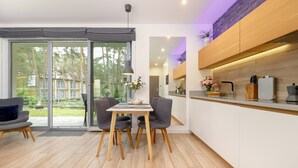 A modern kitchen with white cabinets, a wooden countertop, and a dining area with a table and chairs. - Holiday Apartment Close to a Sandy Beach (Rewal)