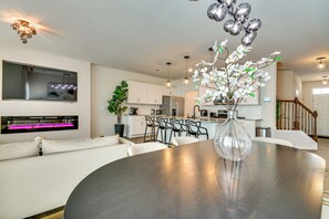 Une cuisine moderne avec des meubles blancs, un coin repas doté d’une table ronde et un escalier menant à un autre niveau.