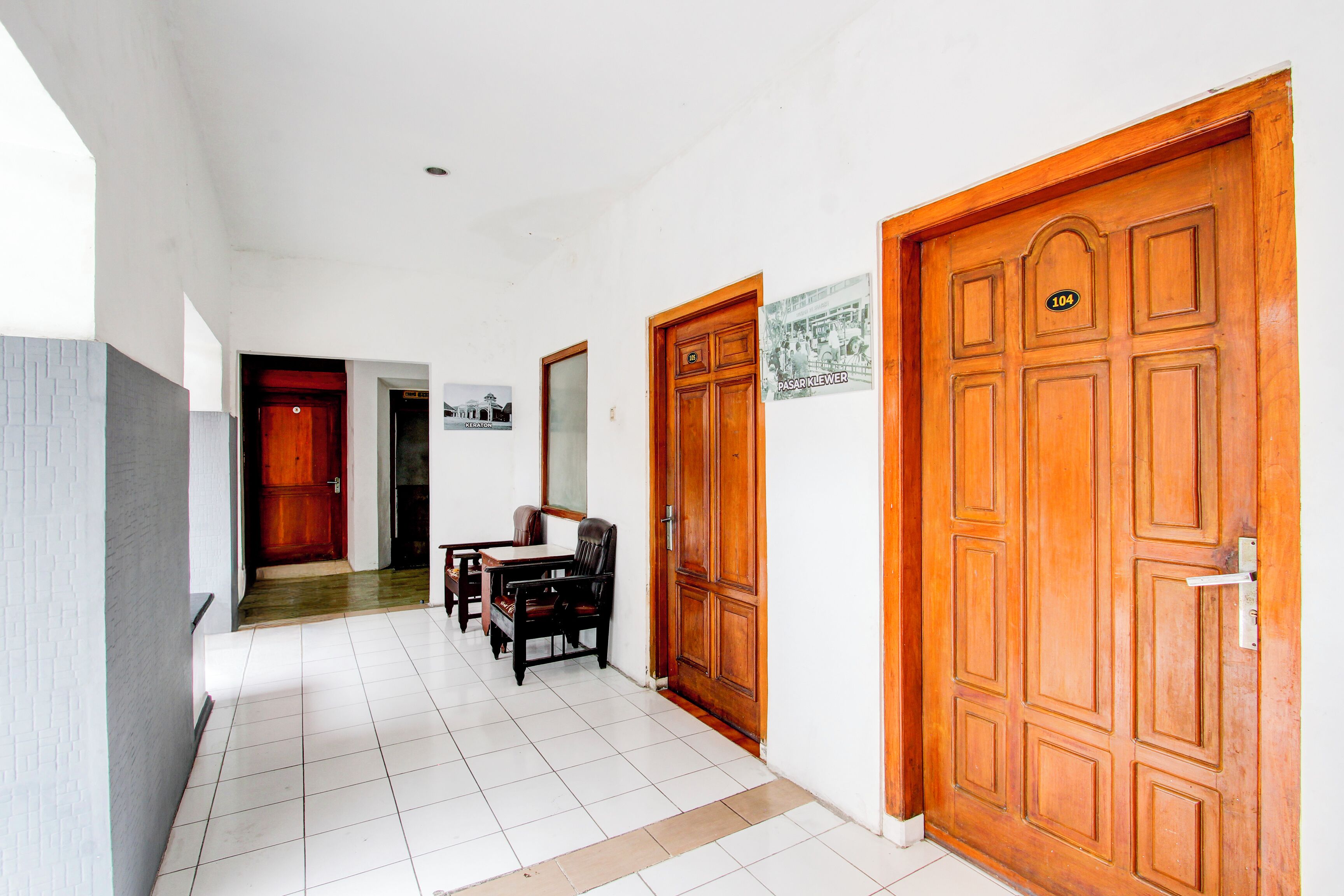 A hallway with a tiled floor, wooden doors, and a dining area with chairs and a table.