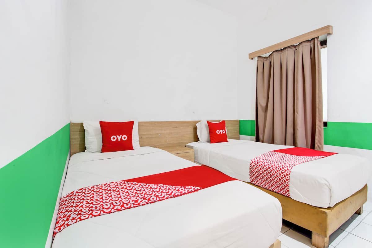 A room with two beds, each with a red and white patterned bedspread, and matching red pillows.