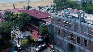 A coastal view with a beach, boats, and a building with scaffolding. - NEO SEA VIEW CONDO (Pattaya)