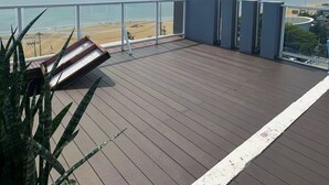 A wooden deck with a view of the beach and ocean. - NEO SEA VIEW CONDO (Pattaya)