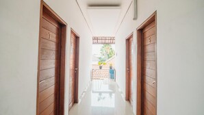 A hallway with wooden doors numbered 6 and 7, leading to a balcony with potted plants. - Aeena Homestay (Ungasan)