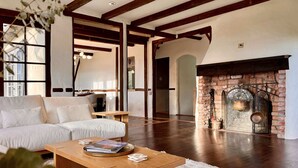 Un salón amplio con un sofá blanco, una mesa de centro de madera y una chimenea con detalles de ladrillo.