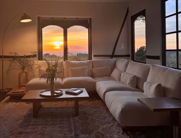 A modern living room with a large window, a sofa, a coffee table, and a floor lamp.