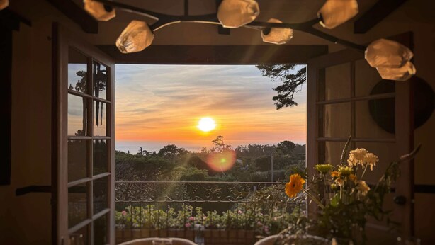 Comedor abierto con vista a un atardecer sobre un paisaje.
