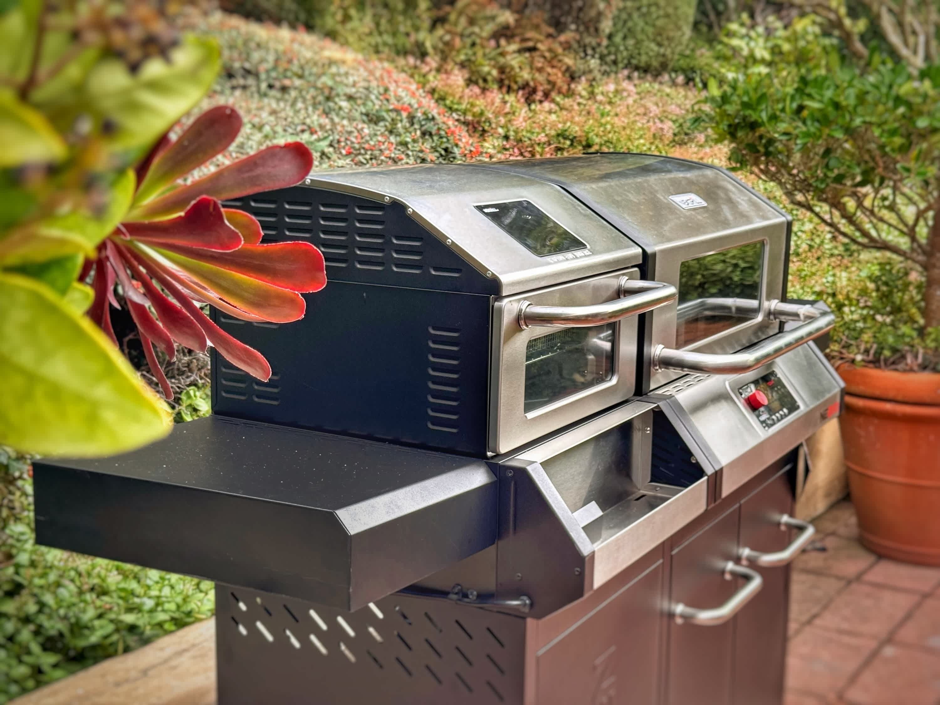 A stainless steel outdoor grill with a digital display, a side burner, and a built-in thermometer.