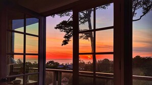 Una habitación con un amplio ventanal que da a un atardecer.