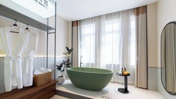 A modern bathroom with a large green bathtub, a wooden vanity, a hanging robe rack, and a large mirror.