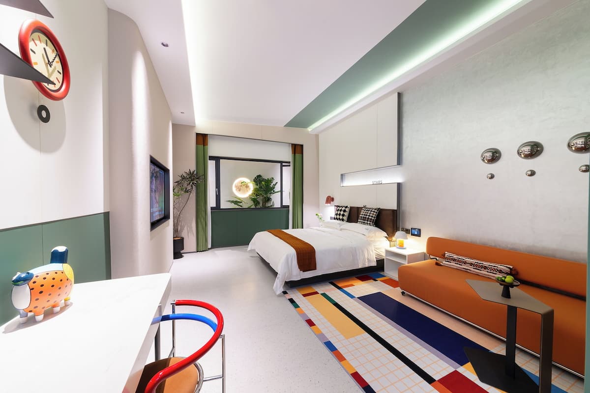 Une chambre d’hôtel moderne équipée d’un lit, d’un canapé, d’un bureau et d’une horloge murale.
