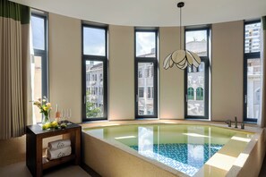 Une salle de bain moderne avec une grande baignoire, de grandes fenêtres et une vue sur les bâtiments environnants.