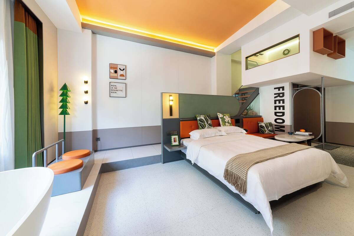 Une chambre d’hôtel moderne équipée d’un lit, d’une table de chevet et d’un petit coin salon.
