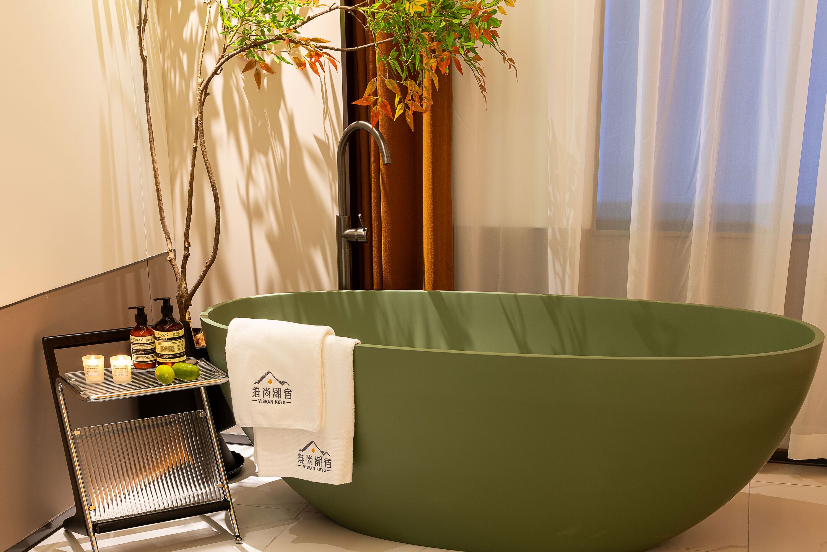 Een moderne badkamer met een groot, groen bad, een klein plankje met toiletartikelen en een plant.