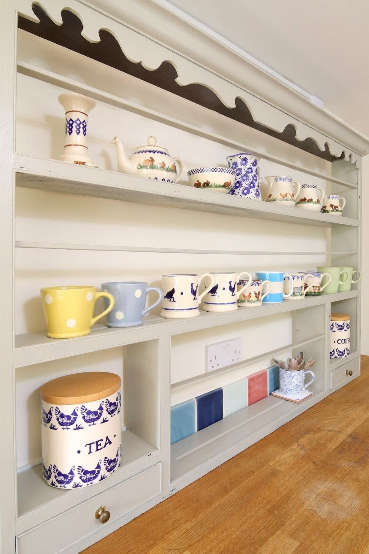 A shelf with various ceramic mugs and a tea canister.