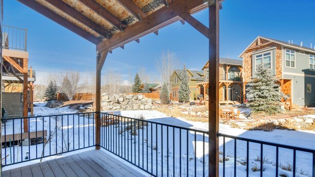 A wooden deck with a metal railing overlooking a snow-covered landscape with houses and trees. - 4 Mi to Granby Ranch: Cabin w/ Hot Tub Access! (Granby)