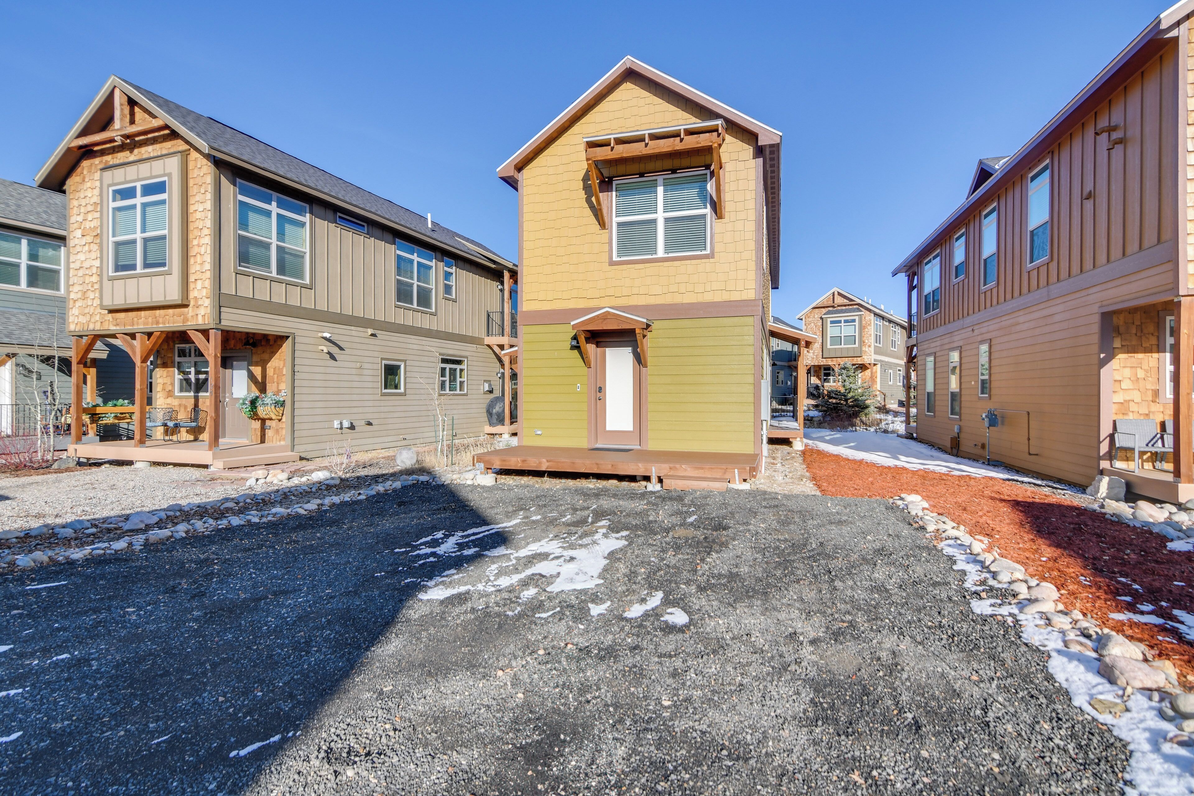 A residential area with houses featuring a mix of siding and stone facades, a gravel driveway, and a clear sky.