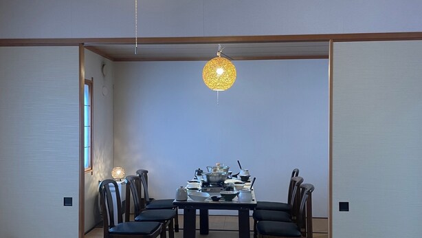 A traditional Japanese-style room with tatami flooring, a low table with a gas stove, and two hanging paper lanterns. - Train Line Field (Tobetsu)
