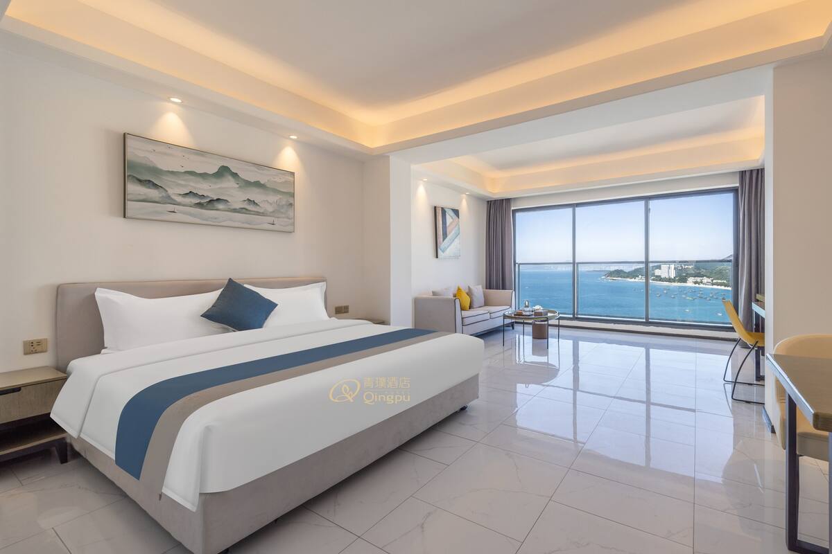 A modern hotel room with a large bed, a view of the sea, and a balcony.