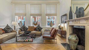 A spacious living room with a fireplace, large windows, and a herringbone wood floor. - The Gallery - Exquisite Apartment, Kensington (Kensington)